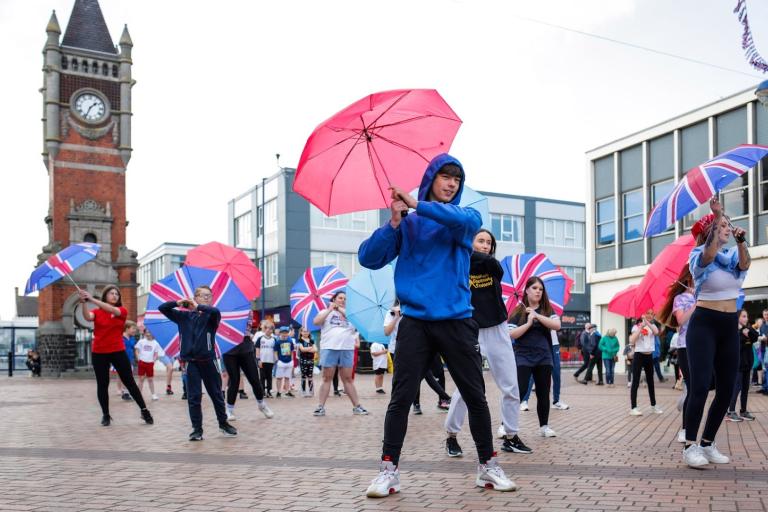 The Imaginarium dancers giving a performance with umbrellas at the flash mob show on Redcar High Street in celebration of the Platinum Jubilee.