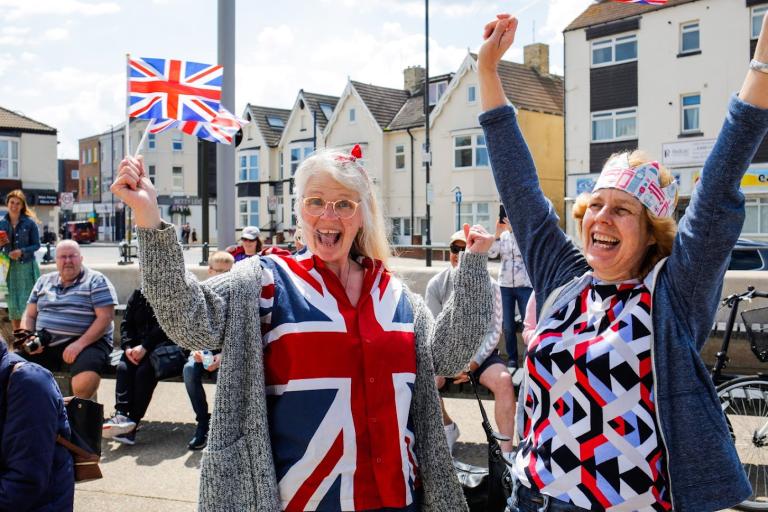 Image showing two ladies at the Town Crier's Declaration, dressed in the British flag being laughing and dancing, excited about the Platinum Jubilee