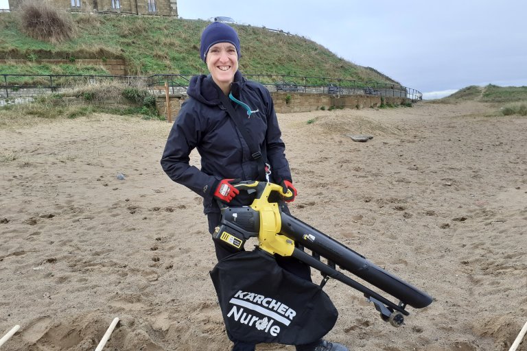 Carolyn Granthier, on the Marske beach using a vaccum to remove microplastics from sand
