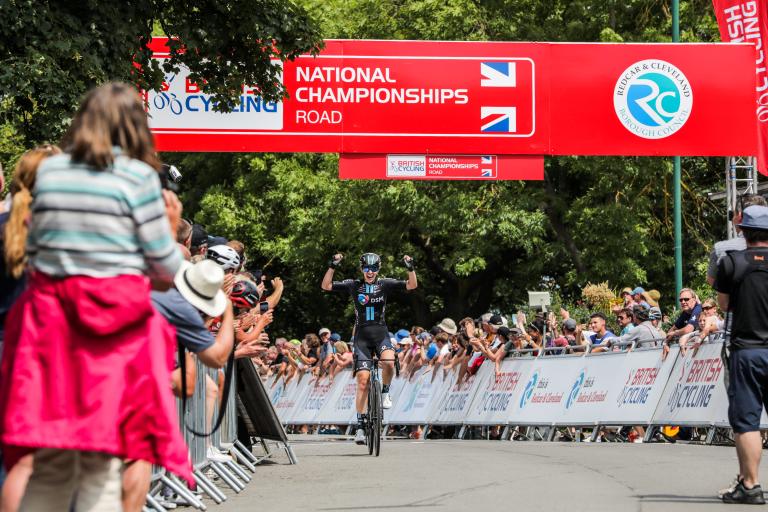 Winner of the Women's Road Race, crossing the finish line while the public applauds her.