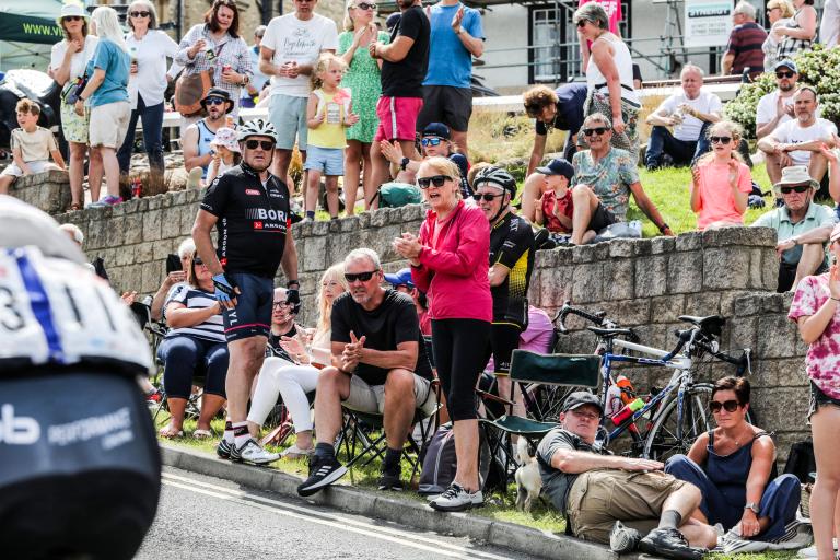 Crowds of people sitting on the side of the road to watch the Road Race