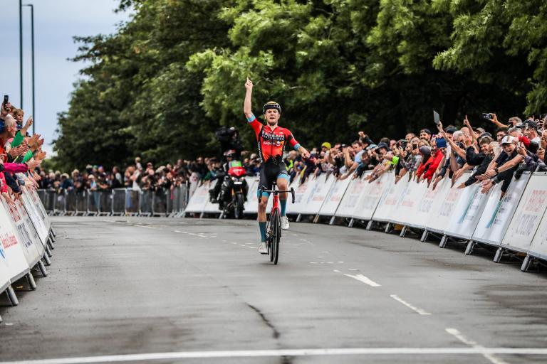 Winner of the Men's Road Race crossing the finish line with crowds cheering for him.