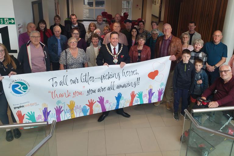 a group of many people smiling to the camera with a banner in front of them that reads: "To our litter picking heroes: Thank you, you are all amazing!""