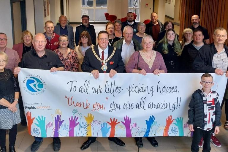 a group of many people smiling to the camera with a banner in front of them that reads: "To our litter picking heroes: Thank you, you are all amazing!""