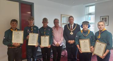 Five young people dressed in scout uniforms standing next to the man whose life they saved and The Mayor of Redcar and Cleveland, Cllr Neil Neil Bendelow