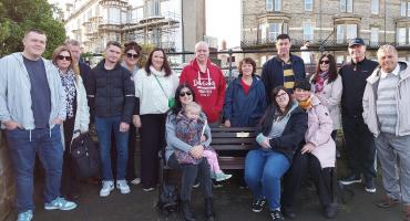 a group of people standing around or sitting on a bench with a memorial plaque engraved on it