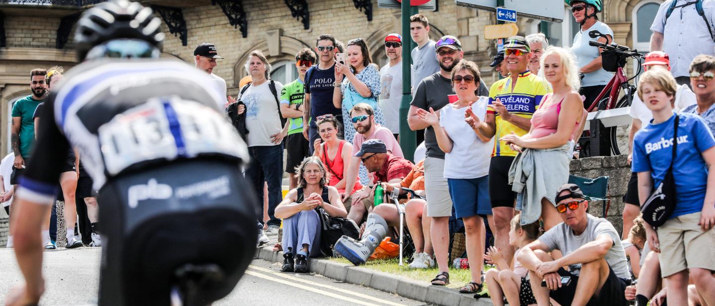 Crowds gathered to see the cyclists in Saltburn. In the foreground you can see one of the cyclists from the back.